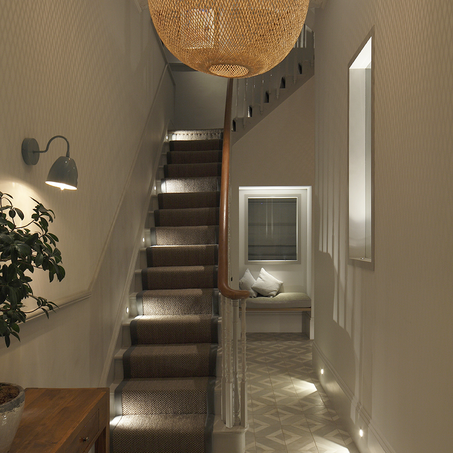 view of hall into stairs with lighting to stair treads