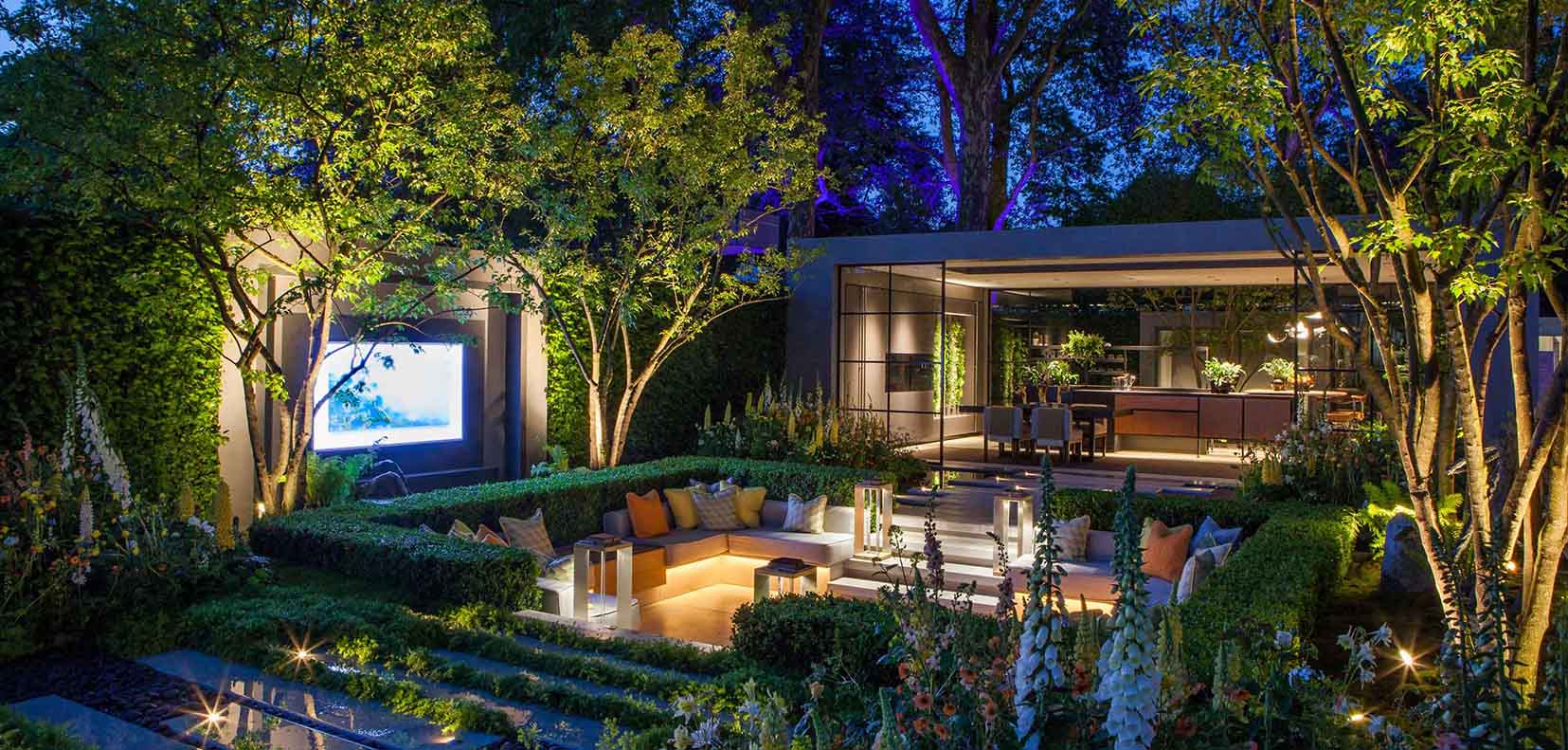 sunken garden with TV screen and uplit trees