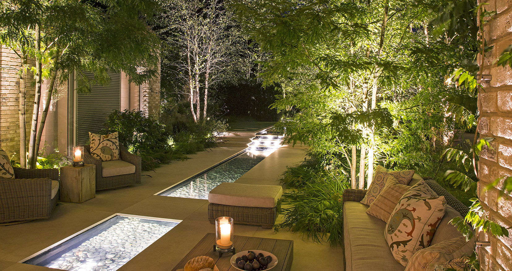 water rill with internal lighting surrounding by lit trees