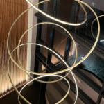 circular pendant fills triple height atrium with uplit wooden wall