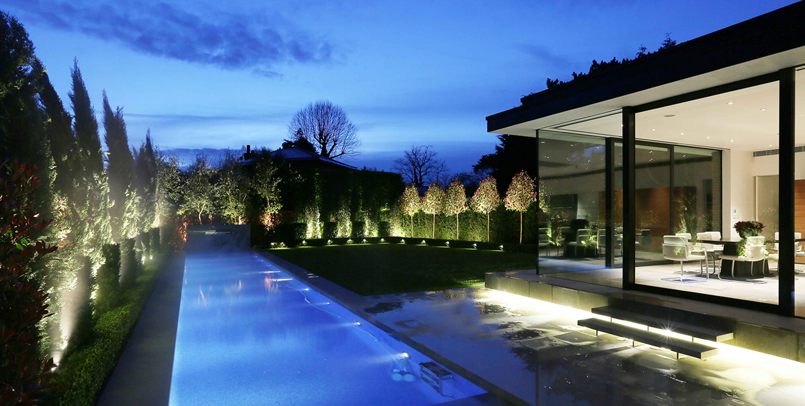 uplit garden surrounding outdoor swimming pool