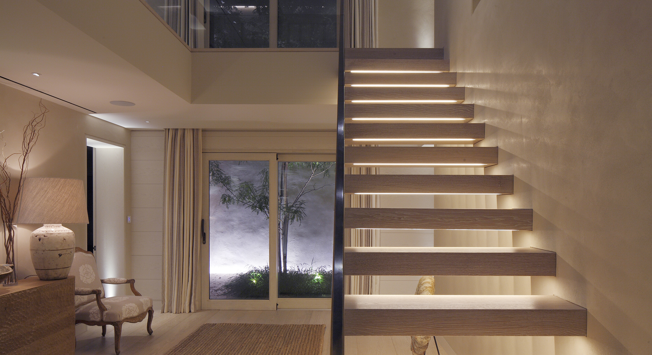 contemporary hall with underlit open stairs and lit courtyard