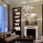 view to lit shelving either side of uplit fireplace with chandelier