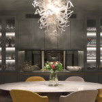 dining room with backlit shelves and large glass chandelier over table