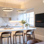 white kitchen with circular decorative pendants above island and strong architectural lighting