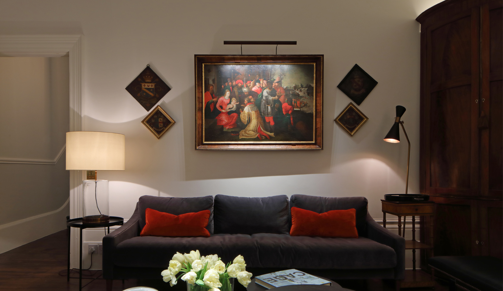 Sofa with painting above lit with picture light and table lamps either side