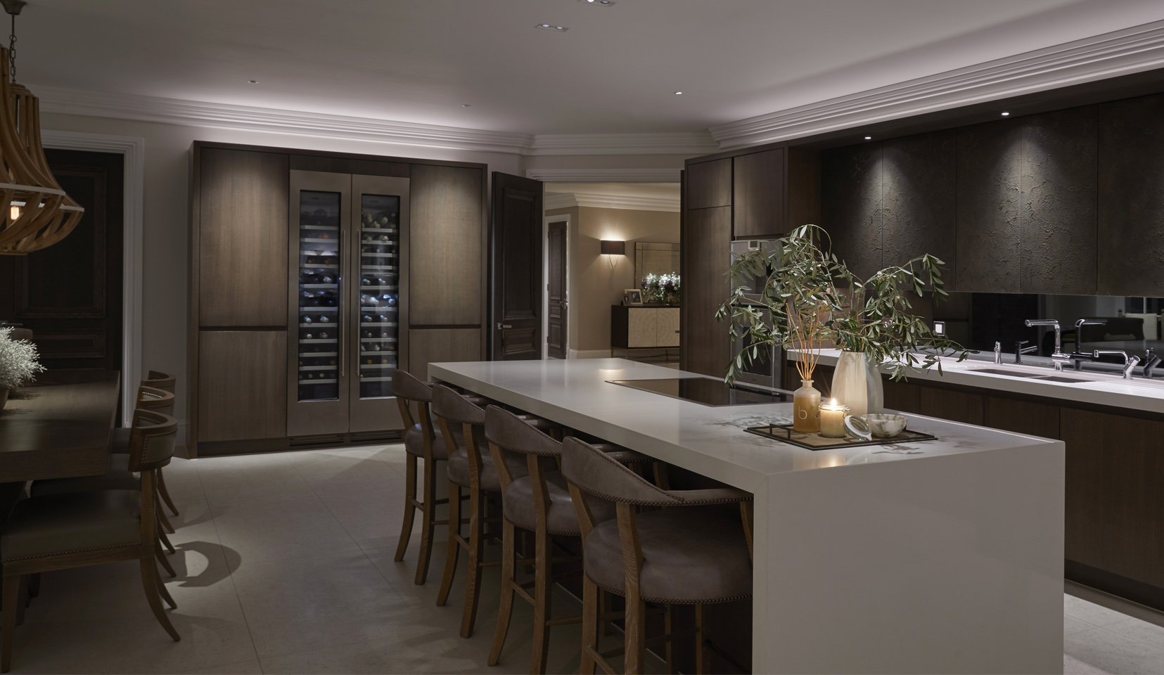Kitchen island with downlights onto counter top and fridge with wine at far end