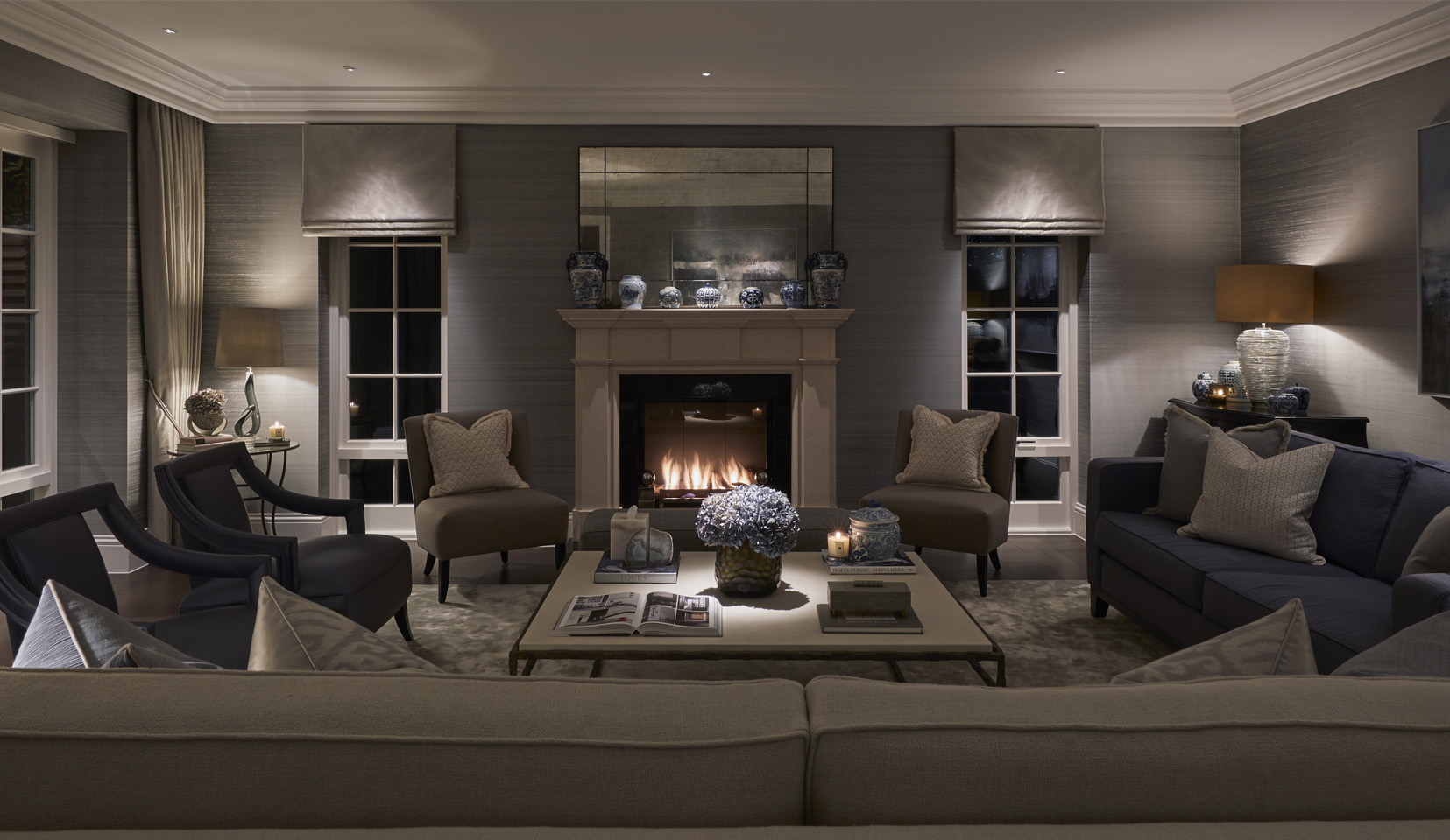 Living room with sofas arounda fireplace and coffee table with flowers lit from downlight above