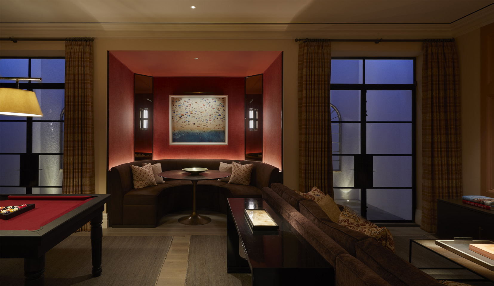 Entertainment room with booth seating area and pool table and light wells lit with uplights