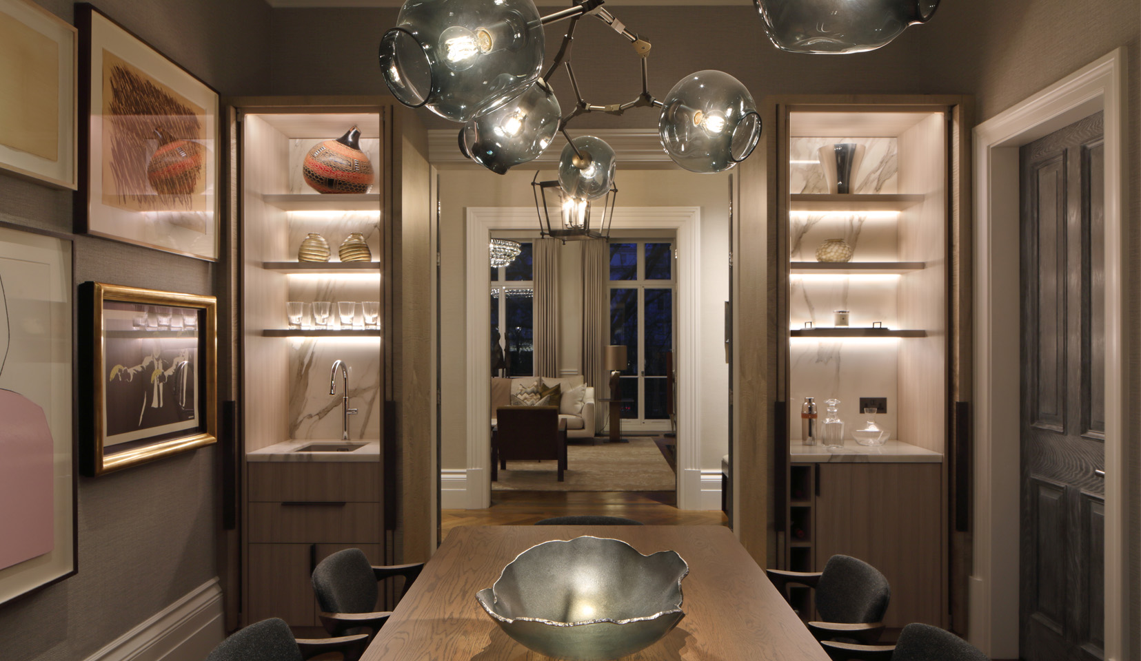 Joinery shelving with objects lit from behind with doorway leading to living room