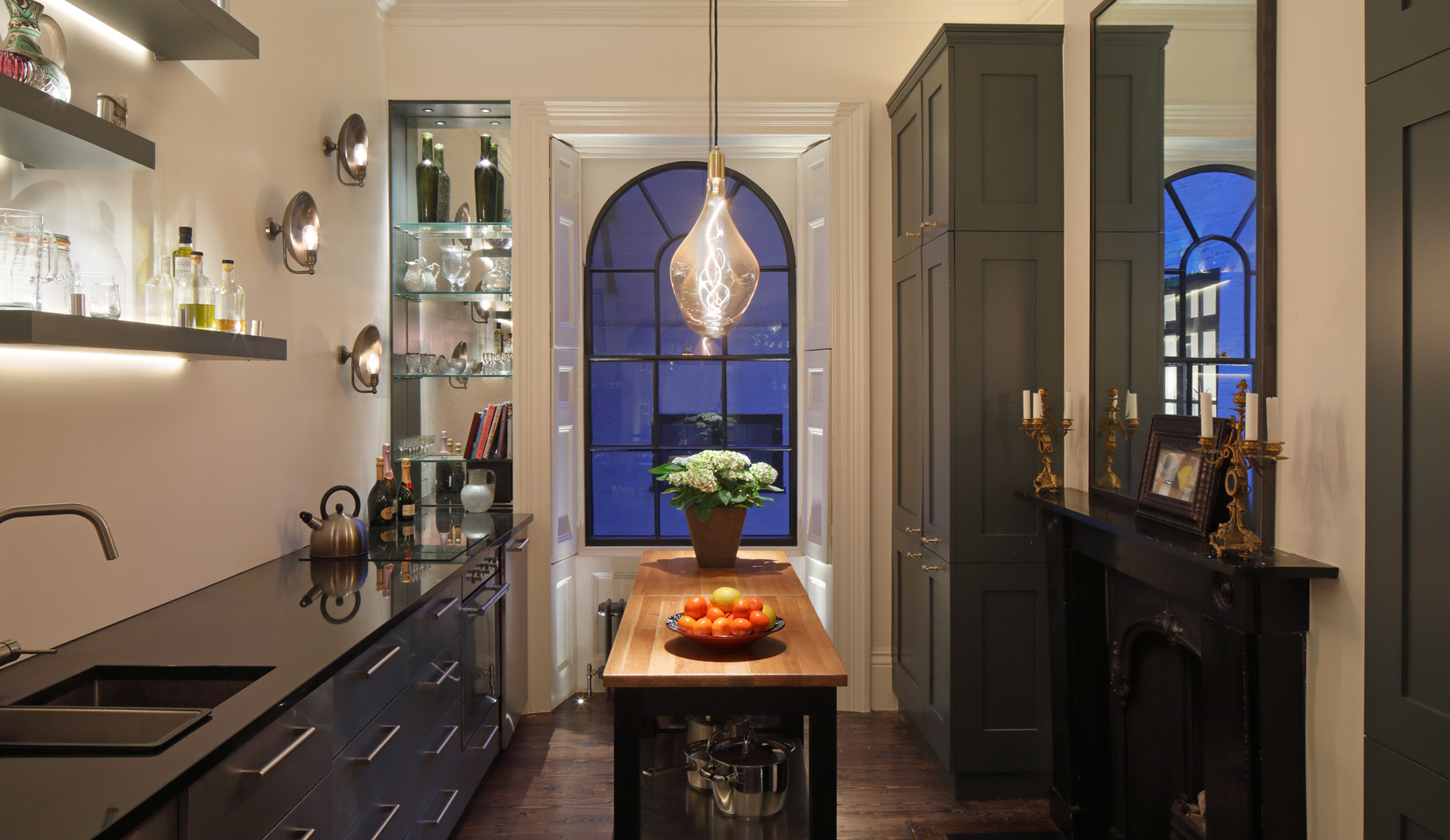 Kitchen with pendant and downlights over the island with shutterboxes lit with uplights in window