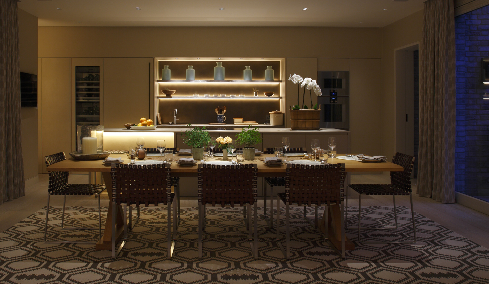Dining room table with bar unit behind and moody evening lighting