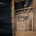 View above staircase with steplights across treads and hanging chandelier through the centre of the staircase