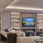 luxury living room with lit coffered ceiling and shelving units