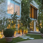 view up drive to contemporary facade with uplit pots and planting