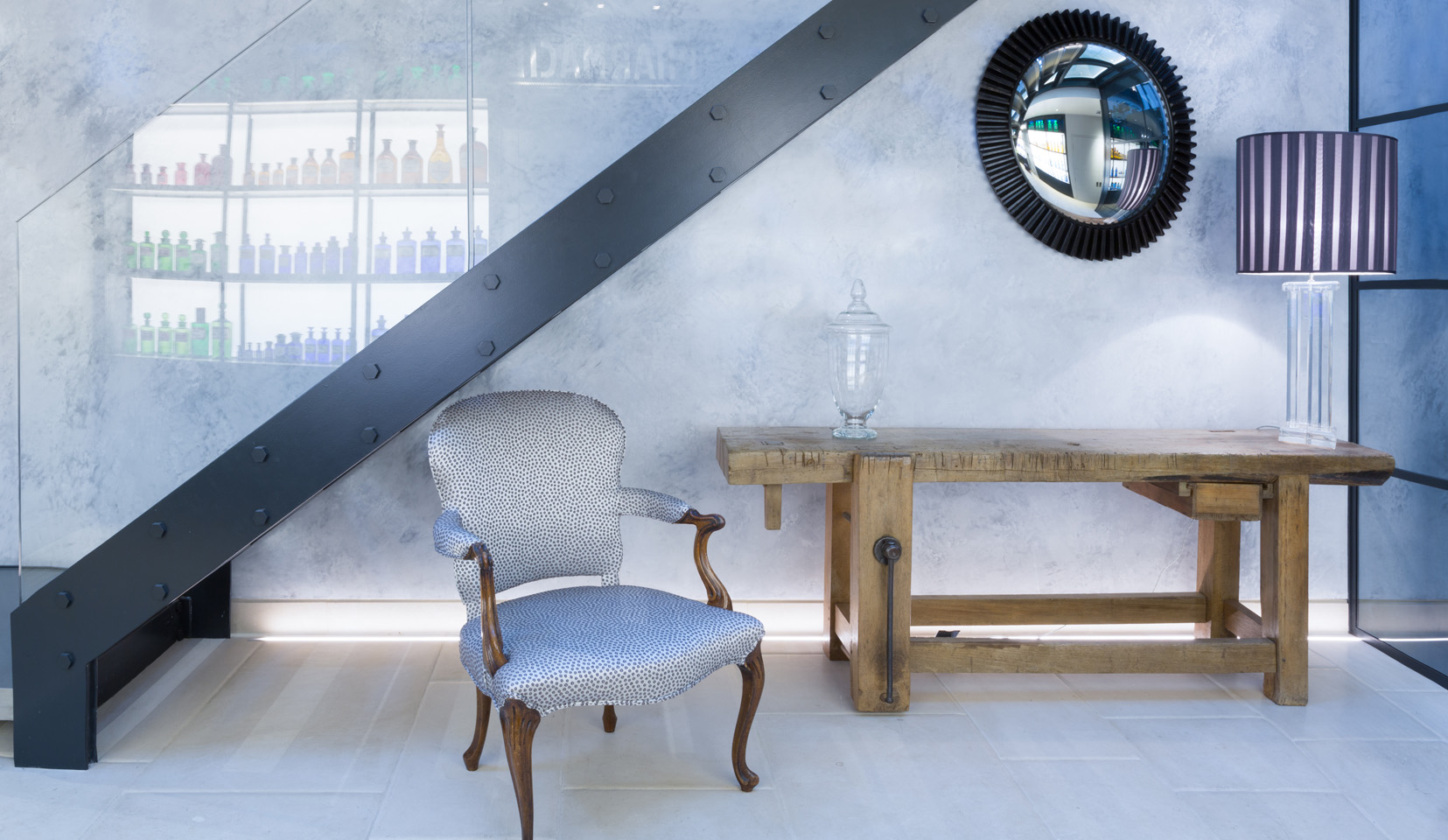View below stairs with chair and table and backlit wall