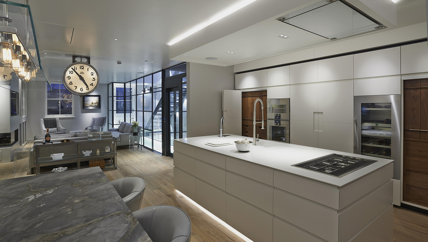 central island of kitchen with downlights over island and lighting cabinets beyond
