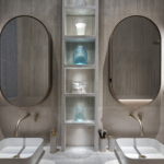 Double sink in bathroom with niches with items lit