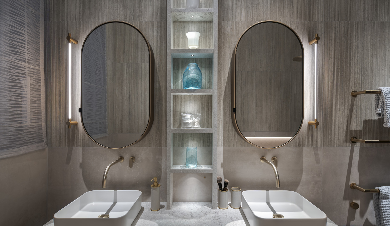 Double sink in bathroom with niches with items lit